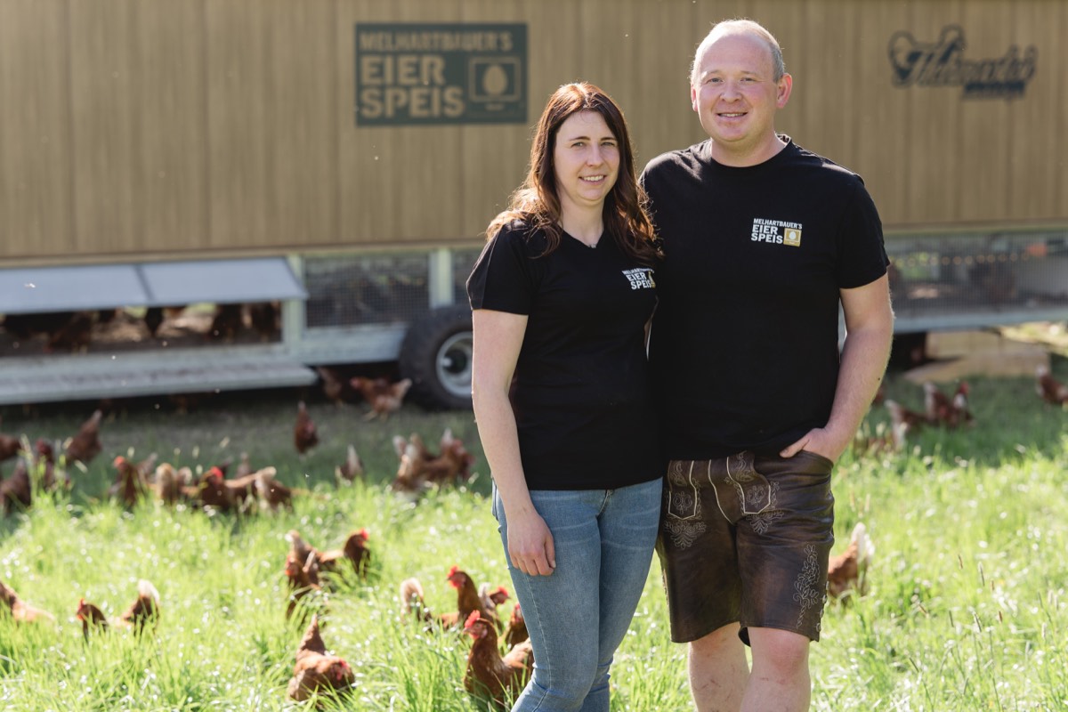 Julia und Stefan Hollrieder vor dem mobilen Hühnerstall mit ihren Hühnern auf der Weide