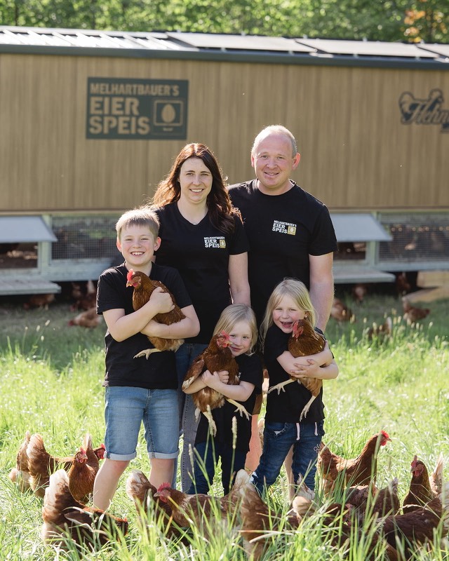 Familie Hollrieder mit H&uuml;hnern vor dem mobilen Stall